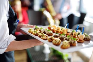 Wait staff carrying plate of appetizers for catering