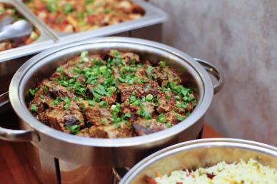 Buffet catering of beef chunks with garnish in metal pots