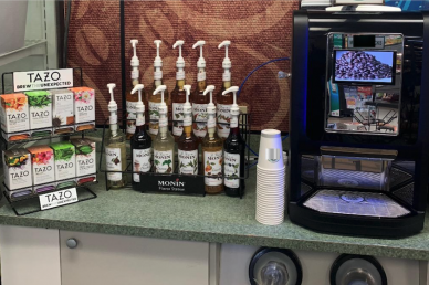 Coffee Bar Kiosk sitting on a counter with different Monin syrup flavors and Tazo teas and cups