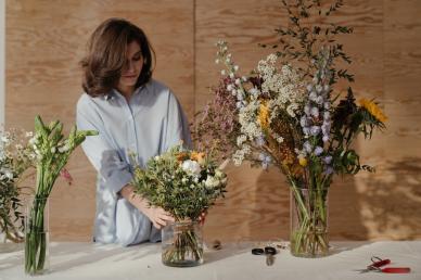 Woman making flower arrangements in three vases