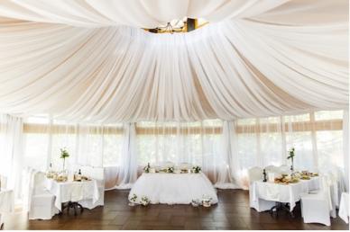 Event tent set up with linen draping and tables and chairs inside the tent