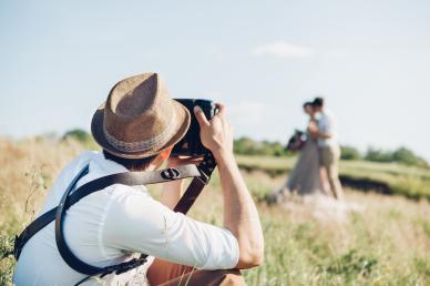 Photographer photographing a couple in a field