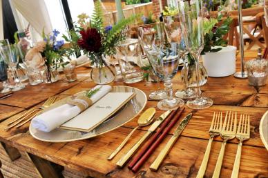 Table setting for dinner party, plates, silverware, and table decor on a wooden table
