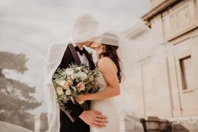 Bride and groom kissing, with flower arrangement in the bride's hand