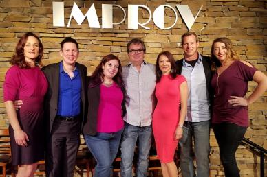 Group of people standing under an Improv sign 