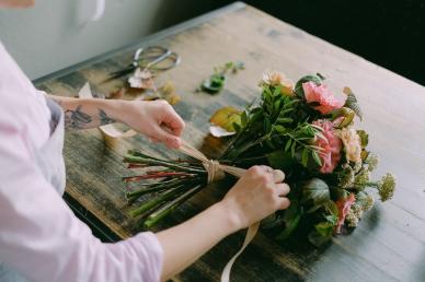 Woman tying a bow around a bouquet of flowers on a table