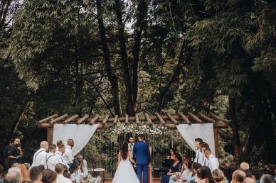 Bride and groom standing at the alter at an outdoor venue with trees in the background