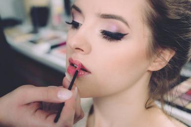 Makeup artist applying lipstick to client