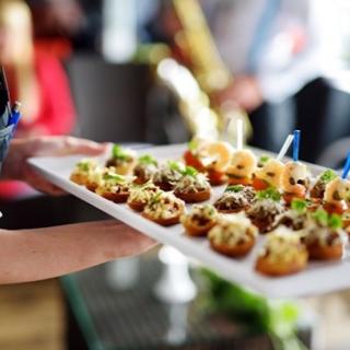 Wait staff carrying plate of appetizers for catering