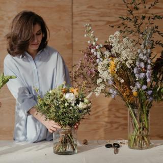 Woman tending ton bouquet of flowers on a table. Three sets of bouquets in vases