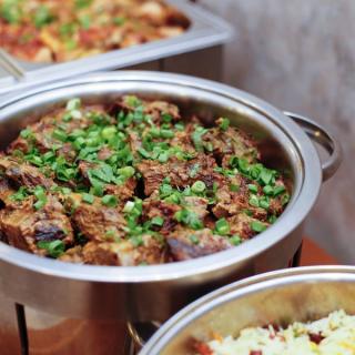 Buffet catering of beef chunks with garnish in metal pots
