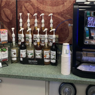 Coffee Bar Kiosk sitting on a counter with different Monin syrup flavors and Tazo teas and cups