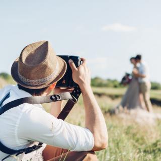 Photographer photographing a couple in a field