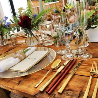 Table setting for dinner party, plates, silverware, and table decor on a wooden table