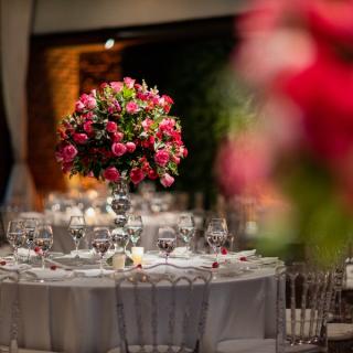 Round tables with large floral centerpieces and white table cloth with place settings