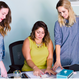 Three women looking at a piece of paper on a desk