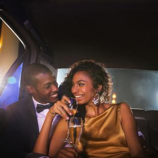 Couple sitting in a limousine as part of their date night, a glass of champagne in the woman's hand