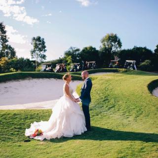 Bride and groom on a golf course, posing for wedding photos
