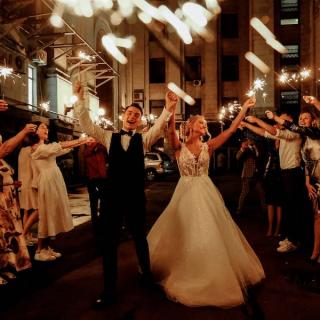 Bride and groom leaving their wedding at night with guests holding sparklers