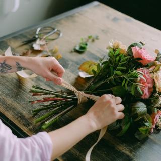 Woman tying a bow around a bouquet of flowers on a table