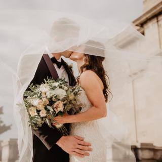 Bride and groom kissing, with flower arrangement in the bride's hand